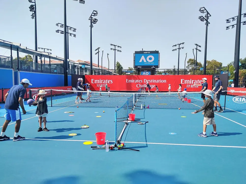 Küçük kortlar ve alçak filelerle çocukların oynadığı bir tenis etkinliği