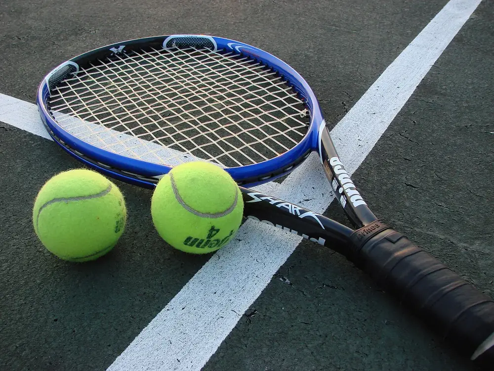 Sert kort zeminde duran tenis raketi ve iki tenis topu
